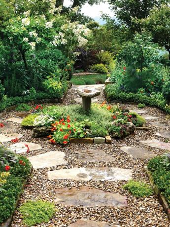Romanttinen kivinen kävelytie käsittää puutarha -suihkulähteen