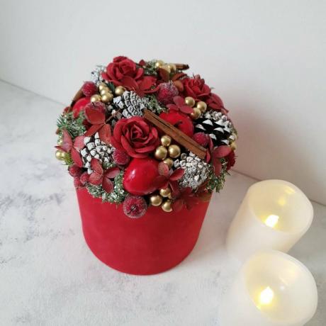 Kerststuk met kaneel en rode bloemen
